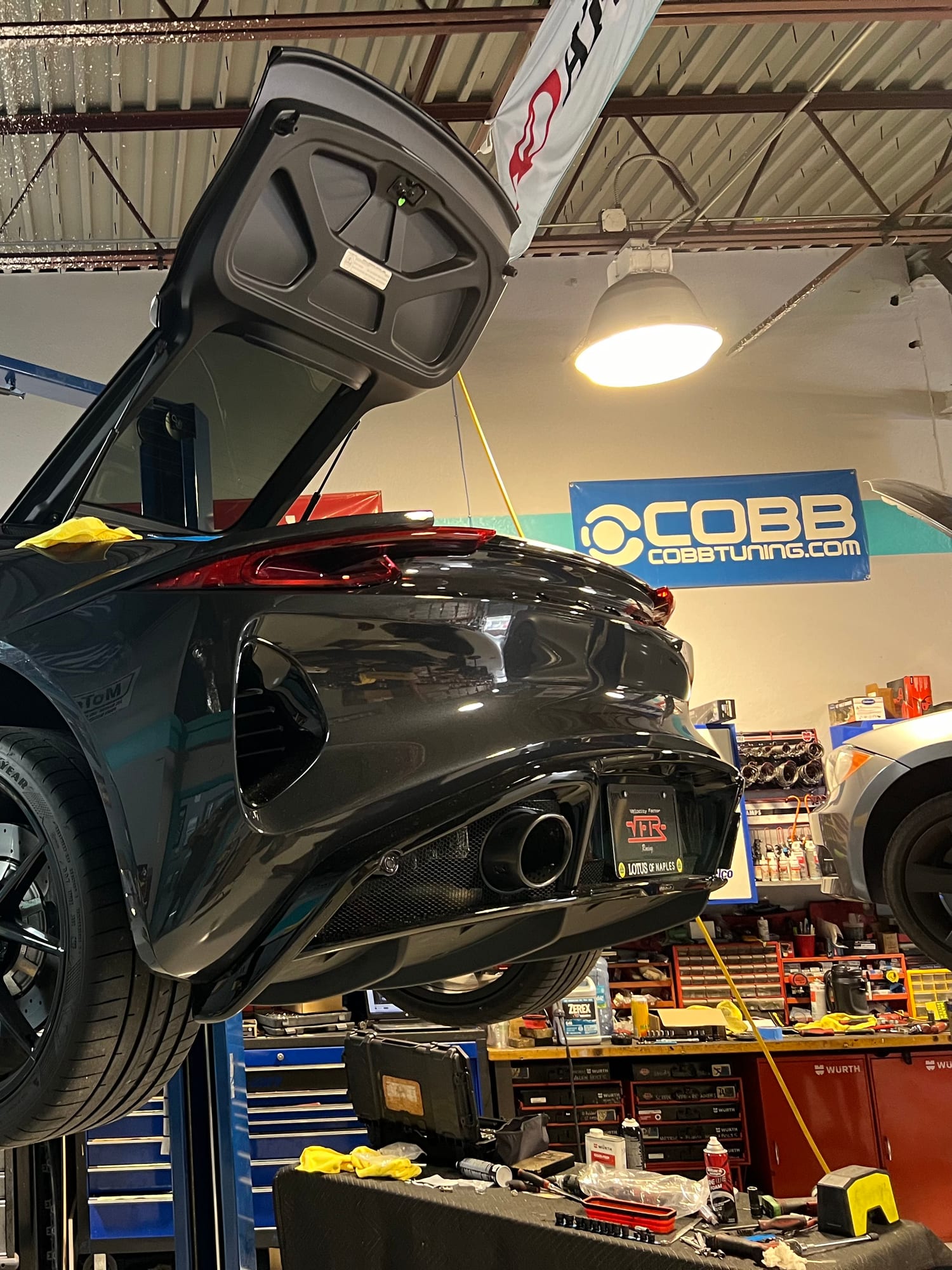 Black Corvette C8 with doors open on a lift inside the Velocity Factor shop