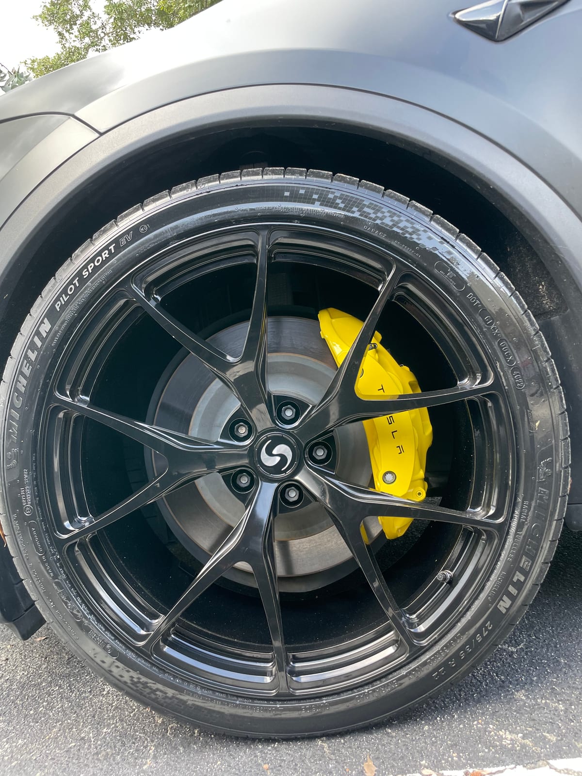 Yellow refinished Tesla brake caliper behind a gloss black wheel at Velocity Factor