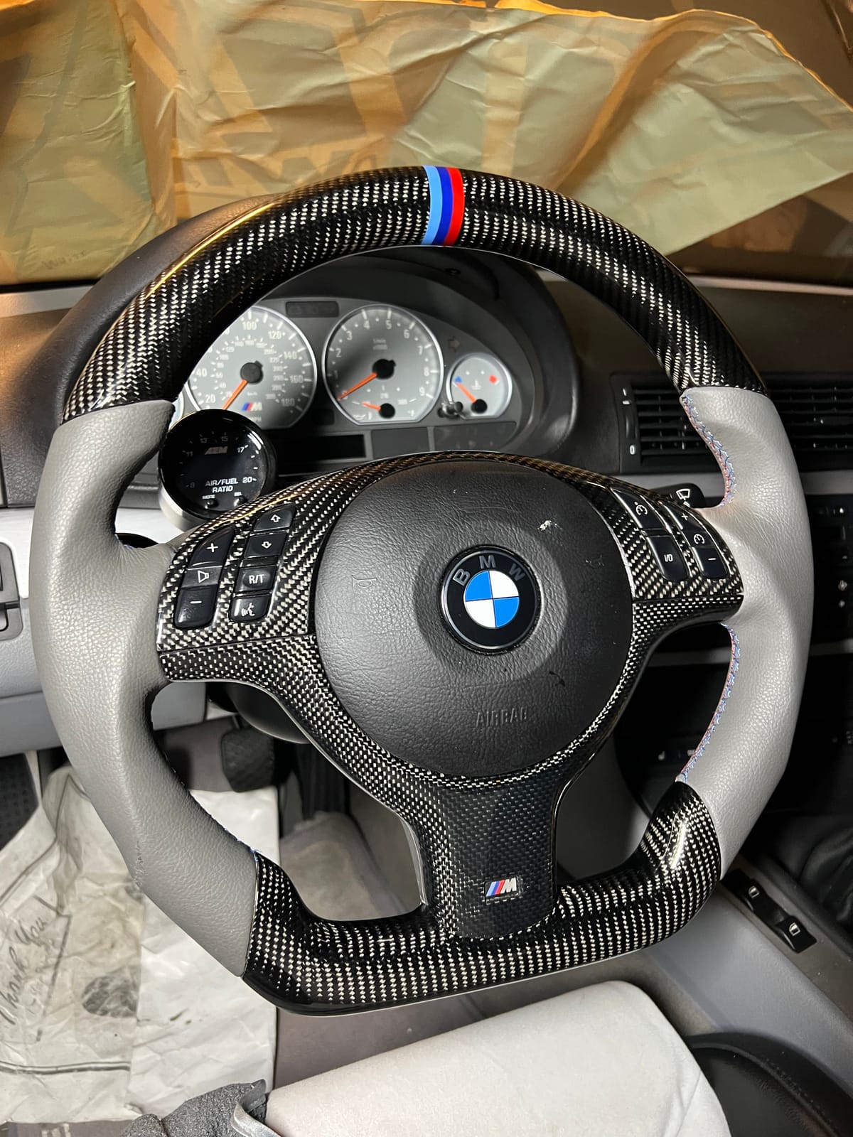BMW E46 M3 custom carbon-fiber steering wheel with M tricolor stripe and gray leather grips at Velocity Factor