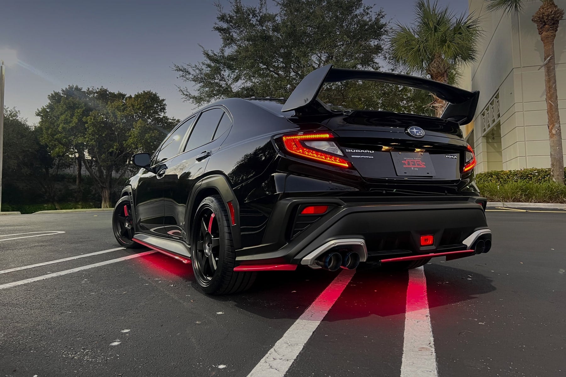 Labor Day Sales Event - black Subaru WRX at dusk with red underglow