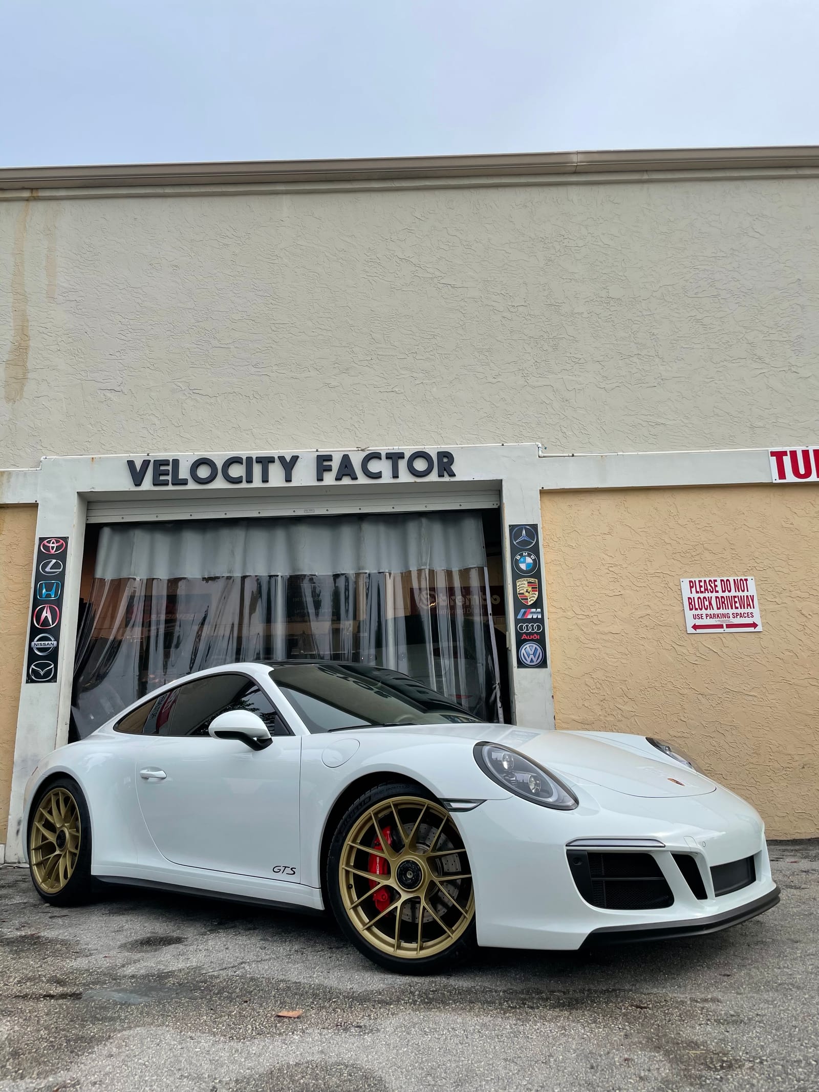White Porsche 911 with gold wheels parked outside the original Velocity Factor storefront in Boca Raton