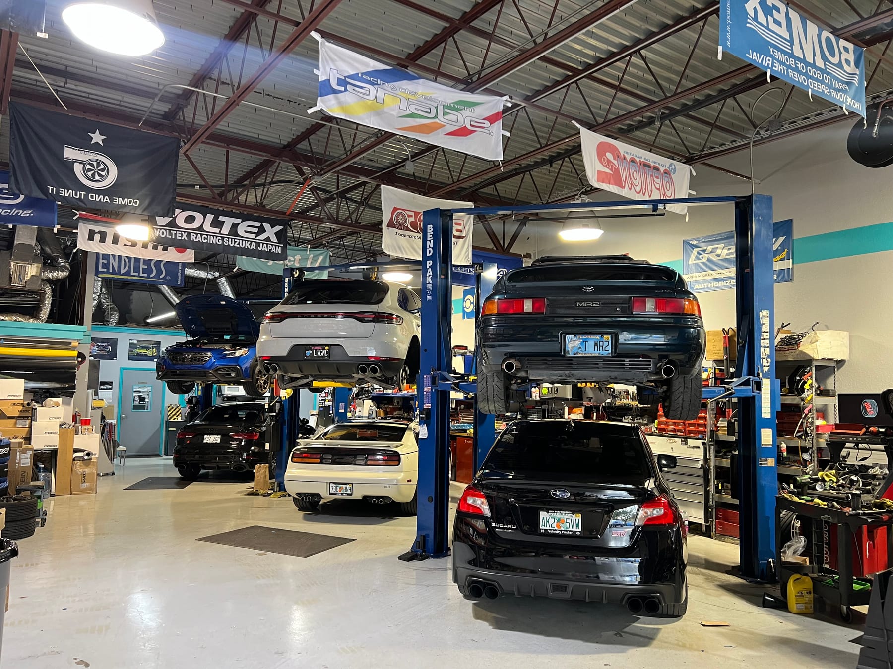 Wide view of the Velocity Factor shop floor in Coral Springs with performance cars on lifts