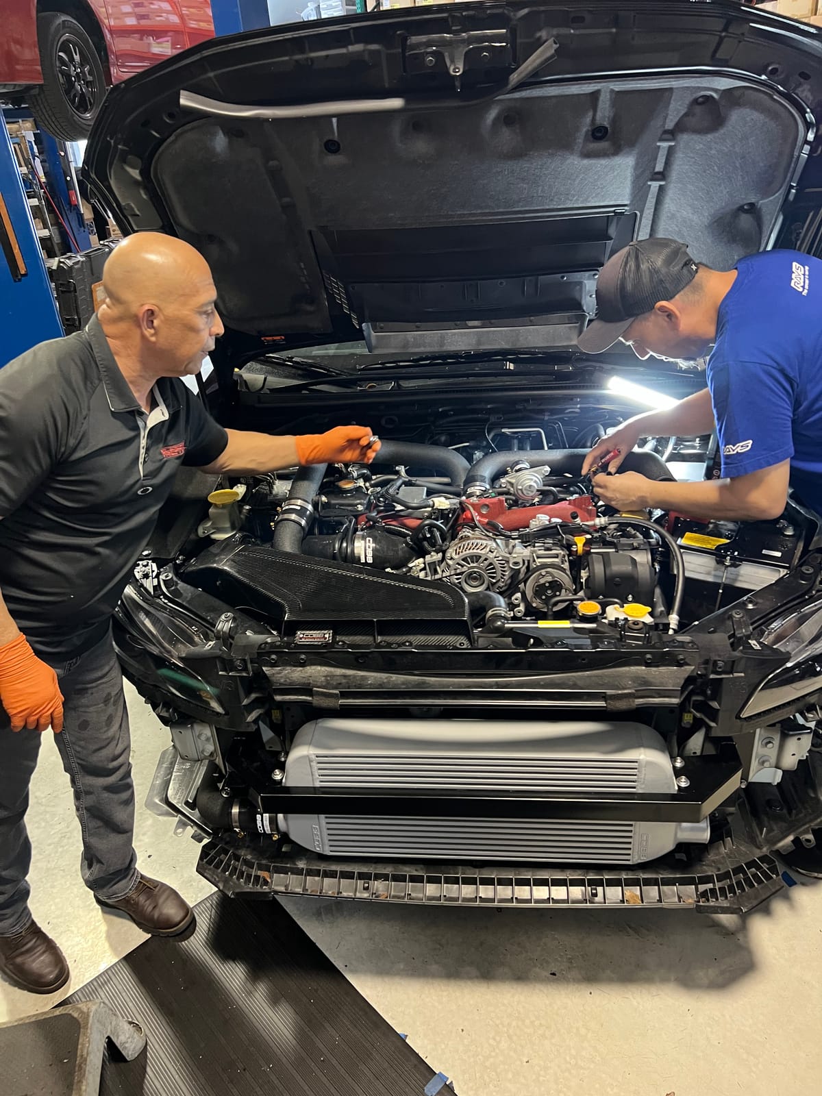 Two Velocity Factor technicians working together on an exposed performance engine