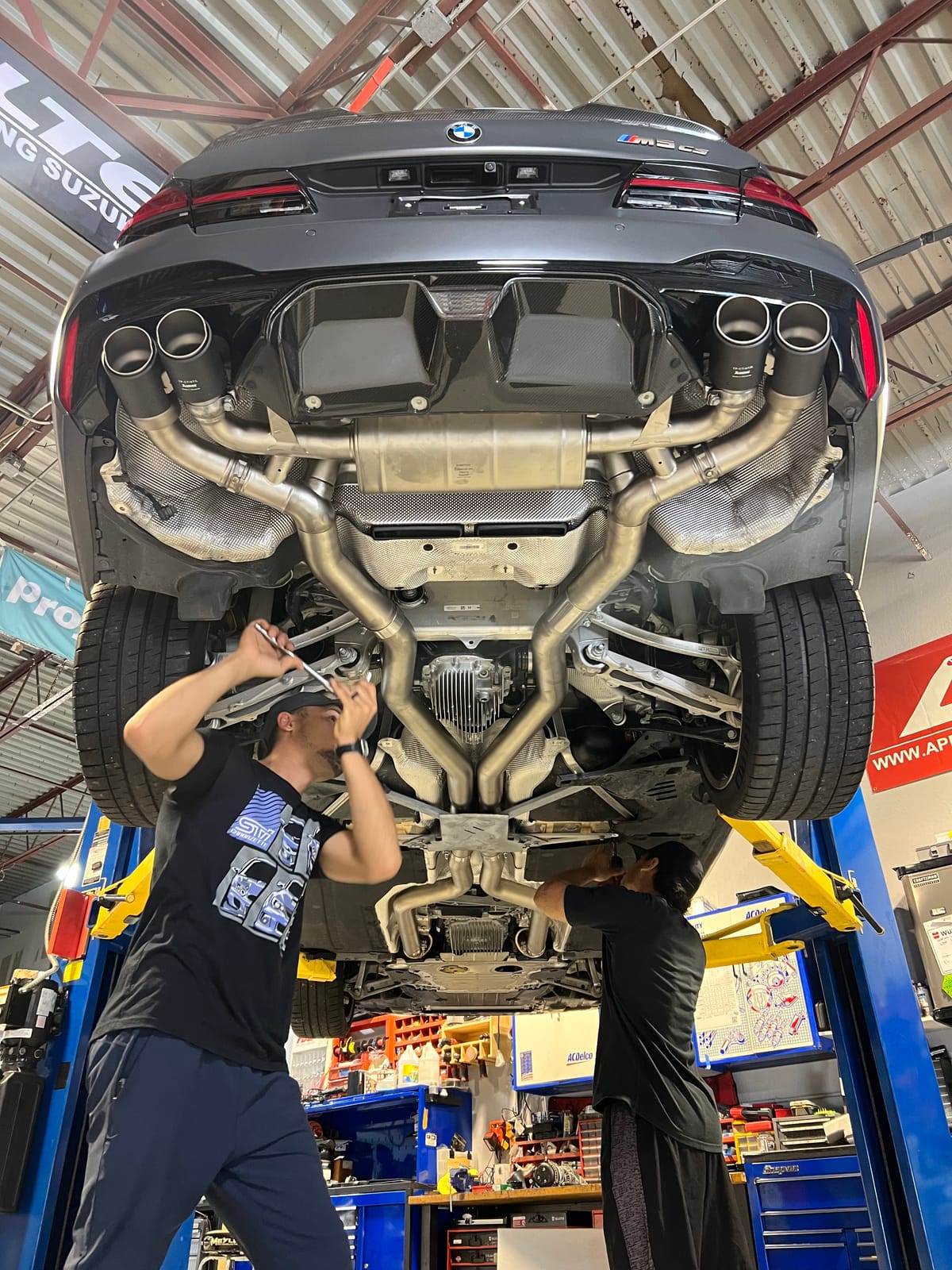Technicians working beneath a BMW raised on a lift at Velocity Factor
