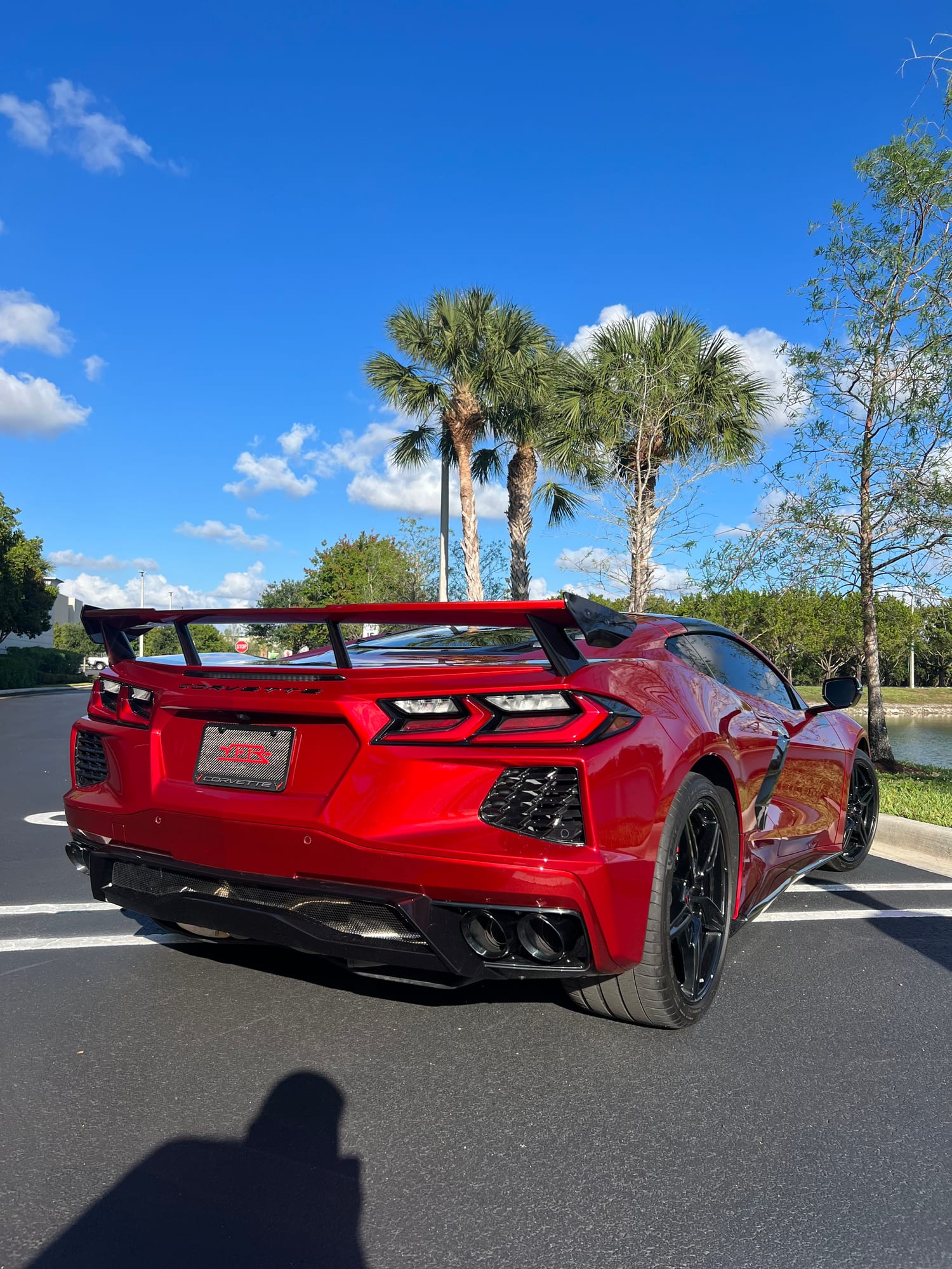 Rear view of a red Corvette C8 Stingray with high wing spoiler and Velocity Factor plate frame