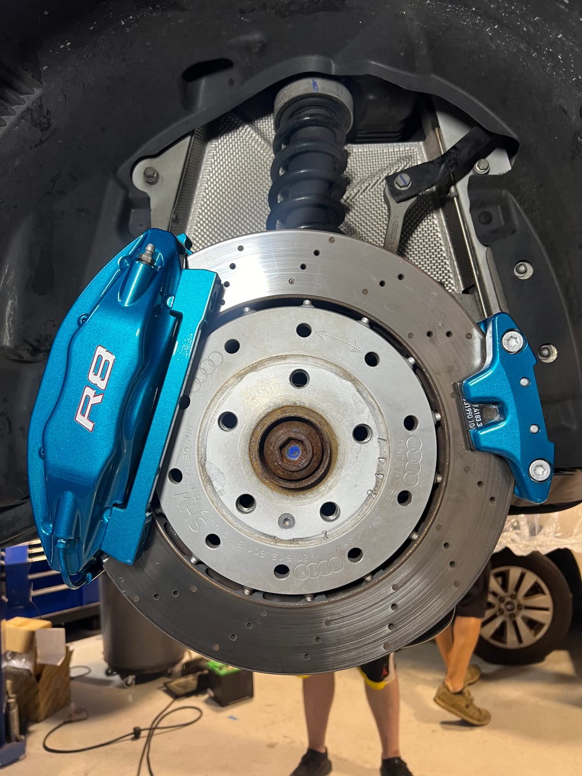 Refinished blue Audi R8 brake caliper with the wheel off during reassembly at Velocity Factor