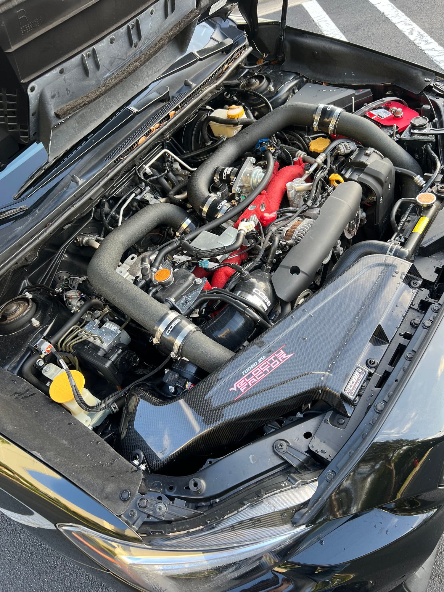 Subaru WRX STI engine bay with carbon fiber Tuned by Velocity Factor airbox and COBB hardware